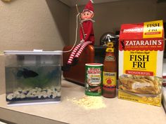 an elf sitting on top of a counter next to fish food and other items in a container