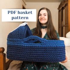 a woman is sitting on the bed holding a blue crochet basket in front of her face