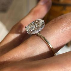 a woman's hand with a diamond ring on top of her finger and an engagement band