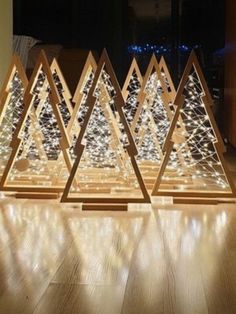 three wooden christmas trees with lights on them in the middle of a wood flooring area