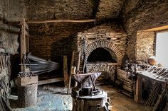 an old stone oven in the middle of a room filled with wood and other items