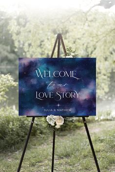 a welcome sign in the grass with flowers on it that says,'we come to love story '