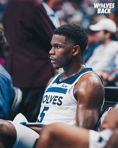 a basketball player sitting on the sidelines in front of an audience with his head down