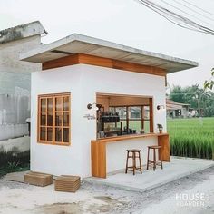 a small white building with two stools in front of it and an outside bar