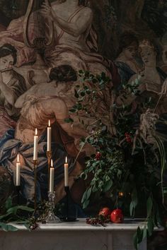 candles are lit in front of a painting on the wall