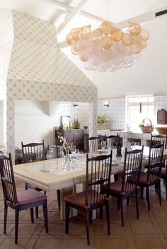 a dining room table with chairs and a chandelier hanging from it's ceiling