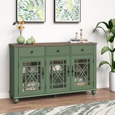 a green cabinet with glass doors in a living room next to a potted plant