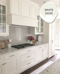 a kitchen with white cabinets and marble counter tops