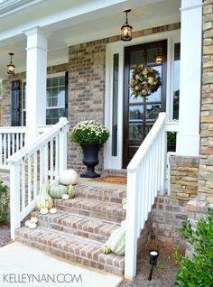 a front porch decorated for fall with pumpkins and gourds