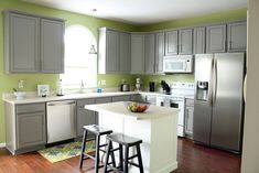 a kitchen with gray cabinets and white counter tops, two stools in front of the island