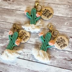 three cactus key chains with tassels on them