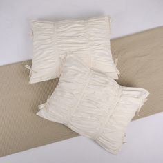 two white pillows sitting next to each other on top of a beige mat and pillow