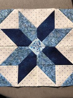 a blue and white quilted star with polka dots on the bottom is sitting on a table