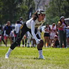 a young woman holding a football on top of a lush green field next to a crowd