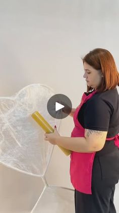 a woman is holding an umbrella and painting it with white paint on the wall behind her