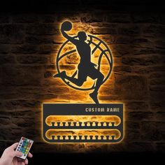 a person holding a remote control in front of a wall with a basketball logo on it