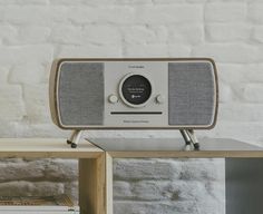 an old fashioned radio sitting on top of a wooden table next to a white brick wall