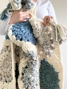 a woman is holding a crocheted blanket in her hands