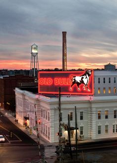 an old building with a neon sign on the roof and a water tower in the background