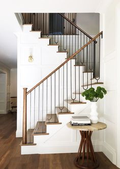 there is a table with books on it in front of the stair case and railing