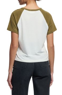 a woman is wearing a white and green t - shirt with an olive colored sleeve