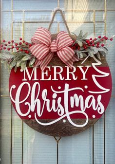 a merry christmas sign hanging on the side of a door with red and white bows