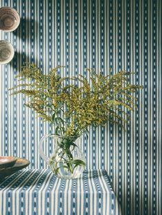 a vase filled with flowers sitting on top of a blue and white striped table cloth