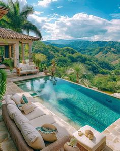 an outdoor swimming pool surrounded by lush greenery and mountains in the distance with chaise lounges around it