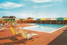 an empty swimming pool surrounded by lawn chairs and colorful shipping containers on the side of it