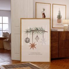 a christmas tree with ornaments hanging from it's branches in front of two framed pictures