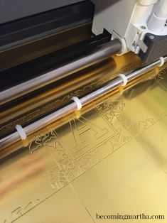 a machine that is cutting some gold paper