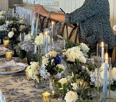 a woman sitting at a table with flowers and candles