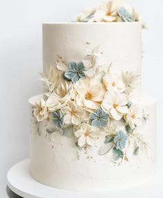 a white and blue wedding cake with flowers on it