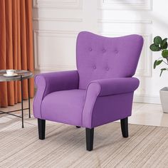 a purple chair sitting on top of a rug next to a table with a potted plant