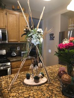 an arrangement of flowers is placed on top of a table in the middle of a kitchen