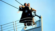 two people standing on the side of a boat looking at something in the air above them