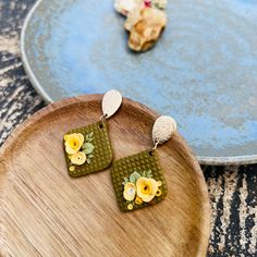 two wooden trays with earrings on them sitting on a table next to each other