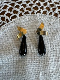 This is a gorgeous pair of vintage NABCO black onyx and 14 karat gold earrings. The art deco earrings are drop style with the black onyx tear drop attached to a beautiful gold ribbon piece. The gold ribbon is attached to post with pushback closure. The earrings are lifted "KM" in the back of the gold, along with "NABCO 14K". These earrings are very elegant and would instantly elevate any special occasion outfit.  Gold and gemstones jeweler verified. This vintage item has been used, but is in exc Onyx Earrings For Evening, Gold Onyx Earrings For Evening, Formal Black Clip-on Earrings, Classic Black Clip-on Earrings For Evening, Vintage Formal Drop Earrings, Formal Vintage Drop Earrings, Classic Onyx Earrings For Evening, Black Enamel Clip-on Earrings For Evening, Vintage Black Enamel Clip-on Earrings