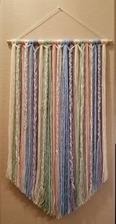 the wall hanging is made from yarn and has multicolored fringes on it