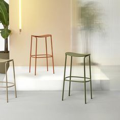 three stools and a table in a room with a plant on the wall behind them