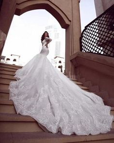 a woman in a wedding dress standing on some stairs with her arms behind her back