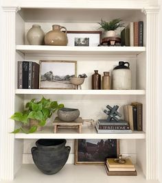 a white book shelf filled with books and vases