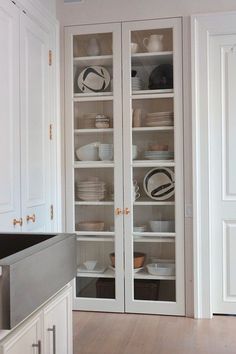 a kitchen with white cupboards filled with dishes