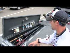 a man sitting in front of an open tool box with fishing rods and lures