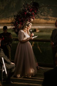 a woman standing in front of a man holding a microphone while wearing a wedding dress