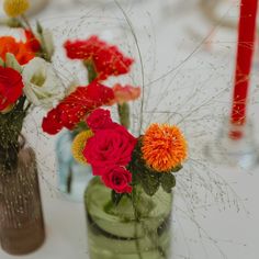 three vases filled with different colored flowers on a table