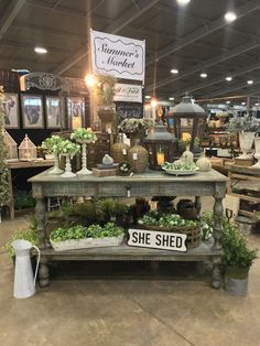 an outdoor market with lots of plants and potted plants on the tables in front of it