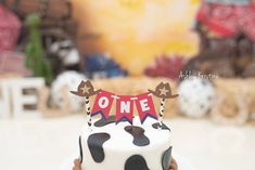 a person holding up a cake decorated like a cow