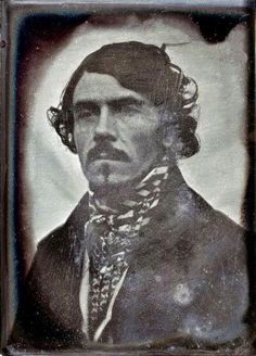 an old black and white photo of a man in a suit with a bandanna around his neck