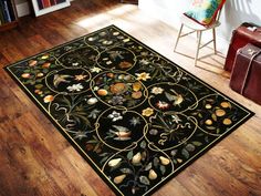 a black area rug with flowers and leaves on it in front of a wooden floor